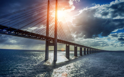 Lange Brücke über das Meer bei Sonnenuntergang mit Wolken am Himmel