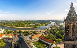 Panoramaansicht einer Stadt mit Fluss und historischer Architektur im Vordergrund.