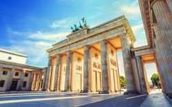 Brandenburger Tor in Berlin bei sonnigem Wetter mit blauem Himmel im Hintergrund.
