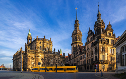 Historische Gebäude und eine Straßenbahn bei sonnigem Wetter in der Stadt Dresden.