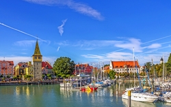 Hafen mit Segelbooten und bunten Gebäuden bei klarem Himmel.