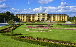 Schloss Schönbrunn mit gepflegtem Garten und blauem Himmel im Hintergrund.