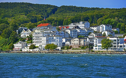 Stadthäuser an einem bewaldeten Hang mit Blick aufs Meer.