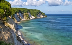 Kreidefelsen an einer Küste mit blauem Meer und bewölktem Himmel.