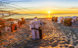 Strandkörbe am Sandstrand von Rügen an der Ostseeküste bei Sonnenuntergang.
