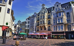 Historische Gebäude in der Bonner Altstadt bei sonnigem Wetter mit Menschen in einem Straßencafé.