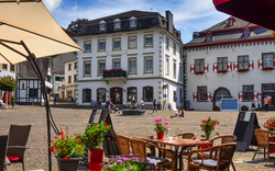 Stadtszene mit Cafétisch und historischen Gebäuden im Hintergrund.