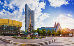 Panorama eines modernen Stadtplatzes mit Wolkenkratzer und Brunnen bei Sonnenschein.