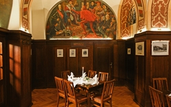Gemütliches Restaurant mit Holzmöbeln und historischer Wandmalerei.