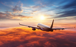 Flugzeug fliegt bei Sonnenuntergang über Wolken am Himmel