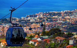 Seilbahn über Stadt mit Meer im Hintergrund.