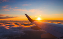 Flugzeugflügel im Sonnenuntergang über den Wolken.